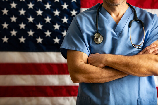 Health: Doctor With Arms Crossed In Front Of Flag