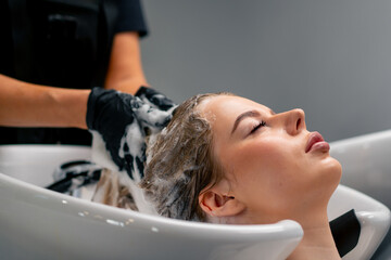 close-up of a hairdresser washing off dye from a client's hair during a care procedure in a salon