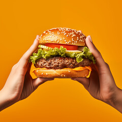 The hands are holding a burger against an orange background