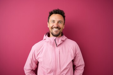 Obraz premium Portrait of a smiling man in his 30s wearing a windproof softshell against a solid pastel color wall. AI Generation