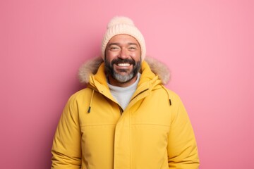 Portrait of a happy man in his 40s wearing a warm parka against a solid pastel color wall. AI...