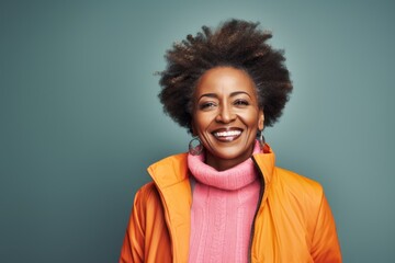 Portrait of a grinning afro-american woman in her 50s dressed in a water-resistant gilet against a...