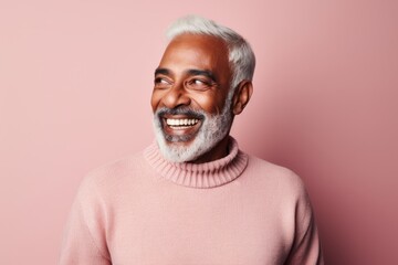 Portrait of a smiling indian man in his 70s dressed in a warm wool sweater against a solid pastel color wall. AI Generation
