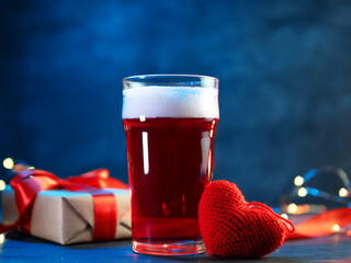 Valentine's day drink. A glass of red craft beer, a gift box and a knitted heart