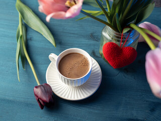 A cup of coffee on a wooden table and a bouquet of tulips. Easter spring composition with tulips