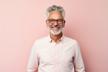 Obraz premium Portrait of a cheerful man in his 60s wearing a simple cotton shirt against a solid pastel color wall. AI Generation