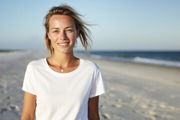 Young beautiful woman wearing casual white t-shirt walking on the beach.