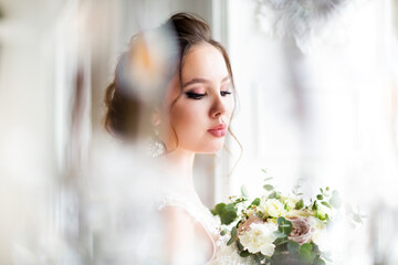 Beautiful brunette woman with bouquet posing in a wedding dress