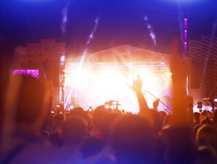 Silhouettes of concert crowd in front of bright stage lights