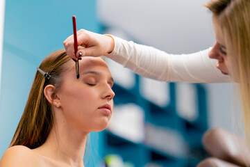 close-up of a make-up artist applying eyeshadow with a brush to a client's face in a beauty salon