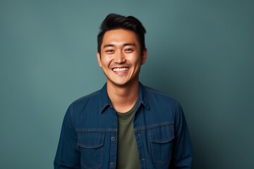 Portrait of a joyful asian man in his 20s sporting a versatile denim shirt against a blank studio backdrop. AI Generation