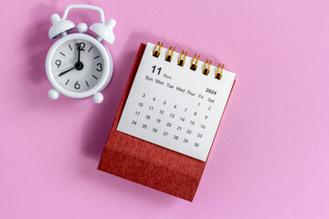 Desk calendar for November 2024 on a pink background.