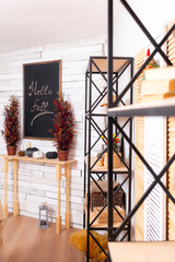 a black chalkboard with a table on the background of a wooden wall. a drawing board with the inscription "hello fall" in the photo studio. Autumn photo zone in the photo salon