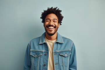 Portrait of a smiling afro-american man in his 20s sporting a rugged denim jacket against a light wood minimalistic setup. AI Generation