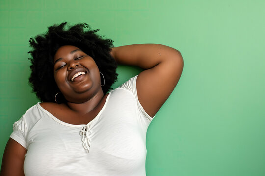 Cheerful overweight African American Woman Enjoying Life with a Big Smile on Green Background