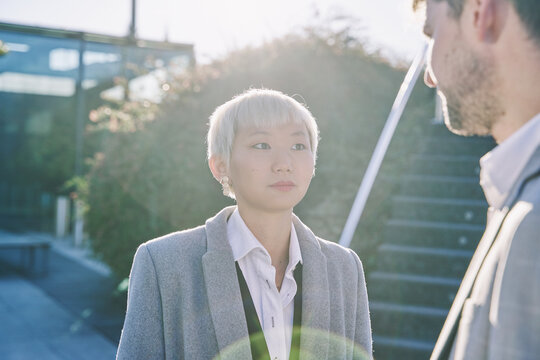 Portrait Of An Asian Woman With White Hair Wearing A Business Suit Talking With Her Partner