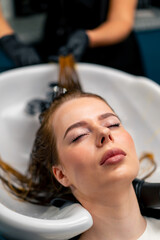 close-up of a hairdresser applying paint to a client's wet hair in a beauty salon makeover