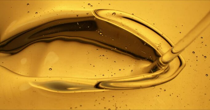Super slow motion macro of fresh bio organic sunflower or arachnid frying oil is flowing dripping liquid oil drops making ripples at 1000 fps.