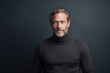 Obraz premium Portrait of a happy man in his 50s wearing a classic turtleneck sweater against a bare monochromatic room. AI Generation