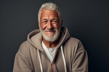 Obraz premium Portrait of a joyful man in his 70s wearing a zip-up fleece hoodie against a bare monochromatic room. AI Generation