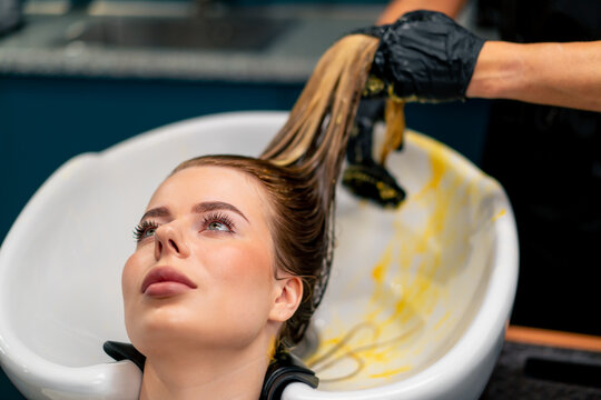 close-up of a hairdresser applying paint to a client's wet hair in a beauty salon makeover