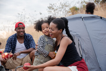 Happy African American family with adorable children enjoy weekend vacation camping outdoors in...