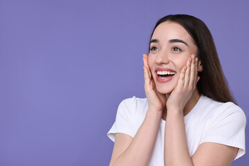 Portrait of happy surprised woman on violet background. Space for text