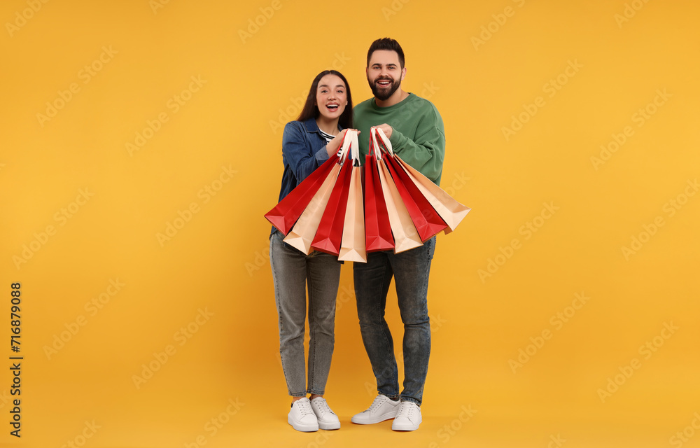 Sticker Happy couple with shopping bags on orange background