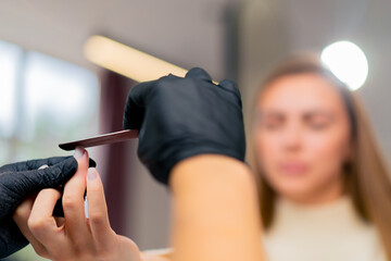 close-up of a manicurist cutting out the shape of a girl's nails with a file a care procedure