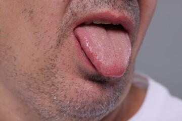 Obraz premium Man showing his tongue on grey background, closeup