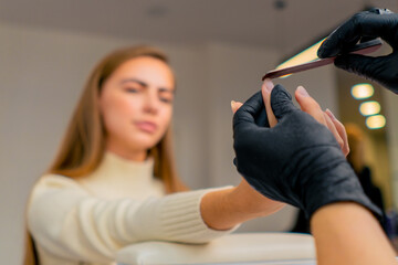 close-up of a manicurist cutting out the shape of a girl's nails with a file a care procedure