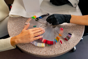 close-up of girl in beauty salon chooses the color of nail polish during a manicure a large palette