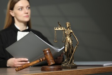 Judge with folder working in courtroom, selective focus. Mallet and figure of Lady Justice on...