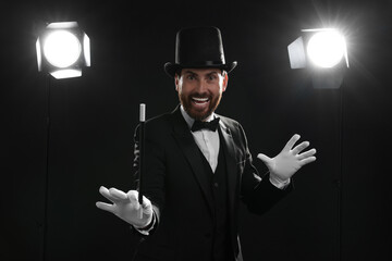 Happy magician in top hat holding wand on stage