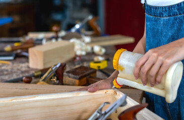 close up of a carpenter using glue working on joining wood in carpentry workplace, diy concept