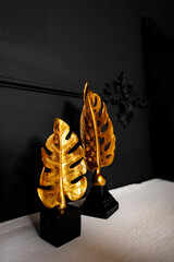 a statuette with golden tropical leaves. the decor on the shelf at home. gilded statuettes in the...