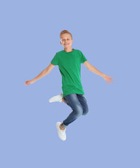 Fototapeta na wymiar Teenage boy jumping on light blue background, full length portrait