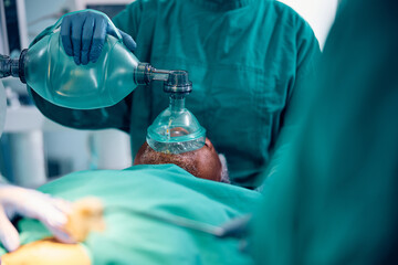 Close up of anesthesiologist using mask on patient during surgery in operating room.