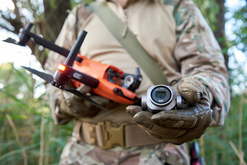 A military soldier, an operator of an unmanned aerial vehicle, holds a camera from a broken...