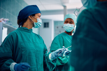 Team of female surgeons working in operating room in hospital. - obrazy, fototapety, plakaty