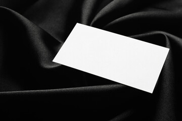 Blank business card on black fabric, closeup. Mockup for design