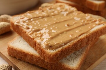 Delicious toasts with peanut butter on table, closeup
