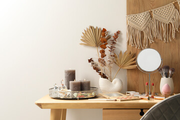 Dressing table with mirror, makeup products and decor in room. Space for text