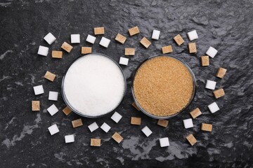 Different types of sugar in bowls on dark gray textured table, flat lay