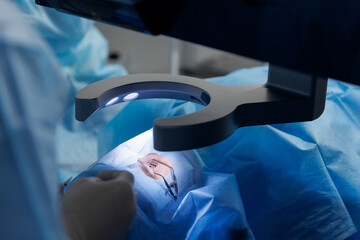 Lasik treatment. Laser vision correction. Doctor examines fundus in microscope, patient under...