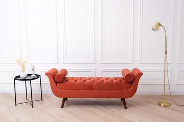 an orange sofa with a black table and a lamp on a white wall. a photo zone in a photo studio in a...
