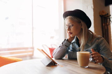 Lifestyle Happy hipster woman use tablet for business startup. Freelancer work and drinking coffee in cafe - obrazy, fototapety, plakaty