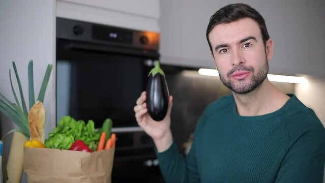 Man showing an eggplant in the kitchen