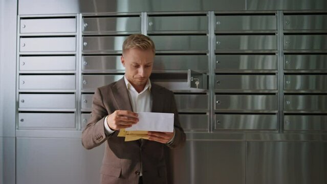 Successful man checking post in office building. Handsome guy looking letters