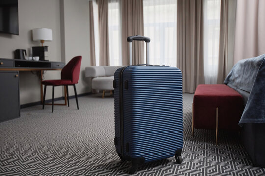 Background image of blue plastic suitcase on floor in luxury hotel room interior, copy space